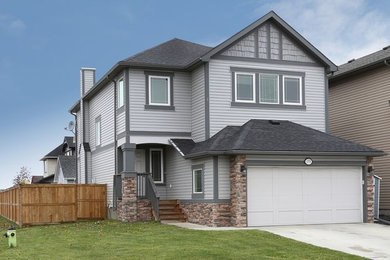 Example of a mid-sized arts and crafts gray two-story vinyl exterior home design in Calgary with a hip roof