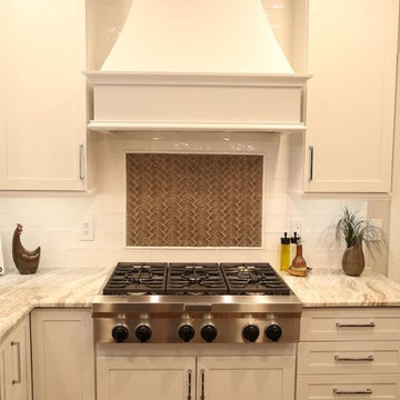 Gas Range with White Hood, White Shaker Cabinets, and Luxurious Marble Counterto