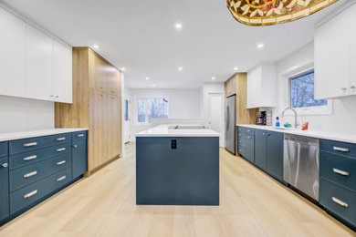 This is an example of a contemporary galley eat-in kitchen in Edmonton with an undermount sink, flat-panel cabinets, blue cabinets, quartzite benchtops, stainless steel appliances, vinyl floors, with island, beige floor and white benchtop.