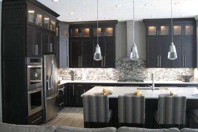 Open concept kitchen - large l-shaped porcelain tile and gray floor open concept kitchen idea in Other with an undermount sink, recessed-panel cabinets, dark wood cabinets, quartz countertops, multicolored backsplash, mosaic tile backsplash, stainless steel appliances and an island