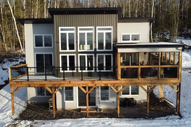 Example of a mid-sized trendy gray two-story vinyl and board and batten house exterior design in Other with a shed roof, a shingle roof and a black roof