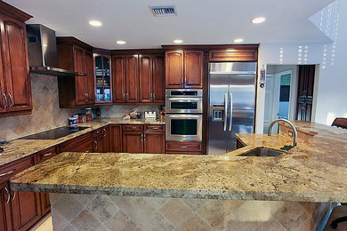 Mid-sized transitional l-shaped ceramic tile eat-in kitchen photo in Miami with raised-panel cabinets, dark wood cabinets, granite countertops, beige backsplash, ceramic backsplash, stainless steel appliances, an island and an undermount sink