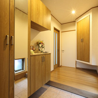 他の地域の中サイズの和風のおしゃれな玄関ホール (白い壁、合板フローリング、木目調のドア、茶色い床) の写真
