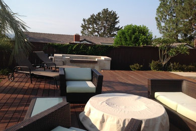 Example of a mid-sized island style backyard deck design in San Diego with a fire pit and no cover