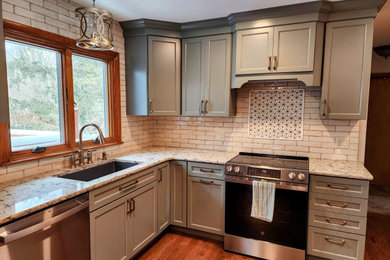 Mid-sized cottage chic l-shaped medium tone wood floor enclosed kitchen photo in Other with a single-bowl sink, recessed-panel cabinets, green cabinets, quartz countertops, beige backsplash, subway tile backsplash, stainless steel appliances, no island and beige countertops