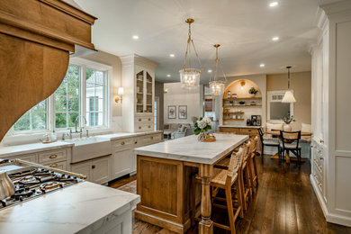 Example of a large country u-shaped medium tone wood floor and brown floor enclosed kitchen design in Philadelphia with a farmhouse sink, beaded inset cabinets, white cabinets, multicolored backsplash, mosaic tile backsplash, paneled appliances, an island and white countertops