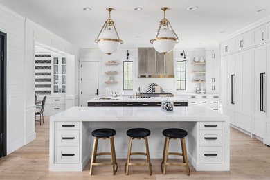 Kitchen - large transitional light wood floor kitchen idea in Phoenix with a farmhouse sink, shaker cabinets, white cabinets, solid surface countertops, white backsplash, porcelain backsplash, stainless steel appliances, two islands and white countertops