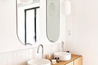 パリにあるおしゃれな浴室 (ダブルシャワー、白いタイル、トラバーチンの床、オーバーカウンターシンク、木製洗面台、洗面台2つ) の写真