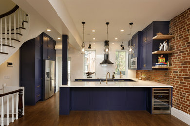 This is an example of a mid-sized contemporary u-shaped eat-in kitchen in New York with an undermount sink, shaker cabinets, blue cabinets, quartz benchtops, white splashback, subway tile splashback, stainless steel appliances, medium hardwood floors, a peninsula, brown floor and white benchtop.
