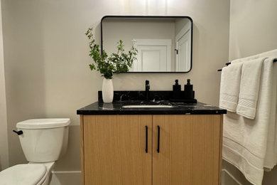 Inspiration for a mid-sized contemporary beige tile and porcelain tile vinyl floor, beige floor and single-sink alcove shower remodel in Other with flat-panel cabinets, medium tone wood cabinets, a two-piece toilet, beige walls, an undermount sink, quartz countertops, a hinged shower door, black countertops, a niche and a freestanding vanity