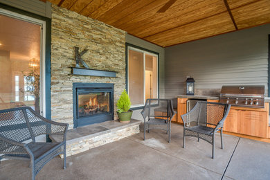 Patio - backyard concrete patio idea in Portland with a fireplace and a roof extension