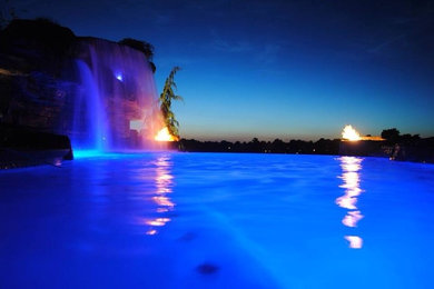 Example of a large mountain style backyard stamped concrete and custom-shaped natural pool fountain design in Other