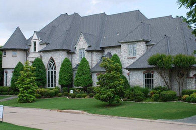 Huge french country gray two-story stone house exterior idea in Dallas with a hip roof, a tile roof and a gray roof