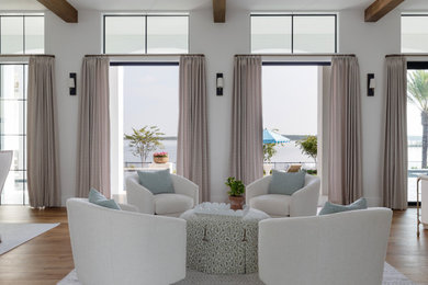 Example of a beach style medium tone wood floor, brown floor and exposed beam living room design in Other with white walls