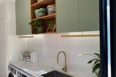 Mid-sized contemporary laundry room in Other with white splashback.