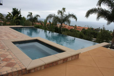 Inspiration for a large contemporary backyard stone and rectangular infinity hot tub remodel in Los Angeles