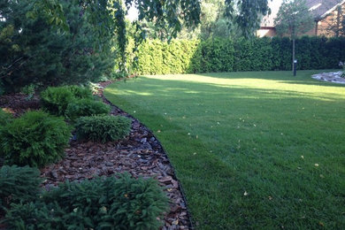 Modelo de jardín de tamaño medio en verano en patio delantero con exposición total al sol y adoquines de hormigón