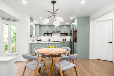 Inspiration for a mid-sized contemporary u-shaped light wood floor and brown floor eat-in kitchen remodel in Calgary with an undermount sink, flat-panel cabinets, green cabinets, quartz countertops, yellow backsplash, subway tile backsplash, stainless steel appliances and white countertops