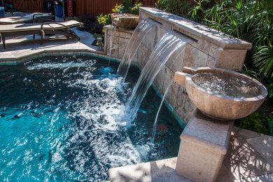 Photo of a small mediterranean backyard custom-shaped natural pool in Dallas with natural stone pavers and a hot tub.
