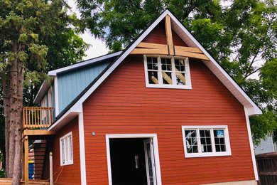 Imagen de fachada de casa roja y negra de estilo de casa de campo de tamaño medio de dos plantas con revestimiento de madera, tejado a dos aguas y tejado de teja de madera