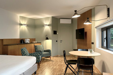 Immagine di un piccolo soggiorno contemporaneo aperto con angolo bar, pareti verdi, pavimento in legno massello medio, TV a parete e boiserie