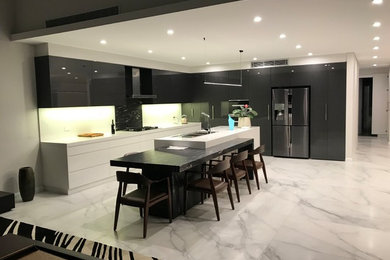 This is an example of a large modern l-shaped eat-in kitchen in Sydney with an undermount sink, flat-panel cabinets, black cabinets, granite benchtops, white splashback, stone slab splashback, stainless steel appliances, with island and black benchtop.