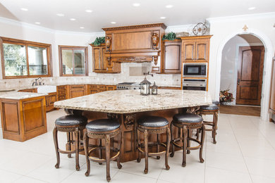 Large elegant l-shaped porcelain tile open concept kitchen photo in Other with a farmhouse sink, recessed-panel cabinets, dark wood cabinets, granite countertops, beige backsplash, ceramic backsplash, stainless steel appliances and an island