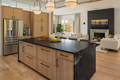 Inspiration for a huge modern u-shaped medium tone wood floor and brown floor kitchen remodel in Minneapolis with an undermount sink, raised-panel cabinets, light wood cabinets, granite countertops, black backsplash, granite backsplash, stainless steel appliances and an island