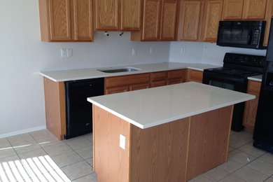 Example of a large arts and crafts l-shaped ceramic tile and beige floor eat-in kitchen design in Phoenix with a drop-in sink, raised-panel cabinets, medium tone wood cabinets, solid surface countertops, white backsplash, black appliances, an island and white countertops
