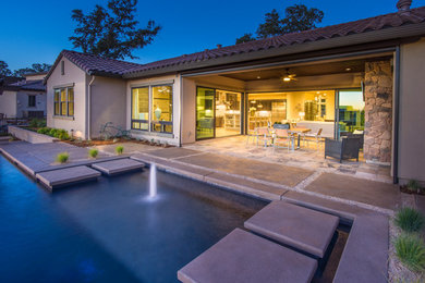 Backyard l-shaped pool in Sacramento with a water feature and concrete pavers.
