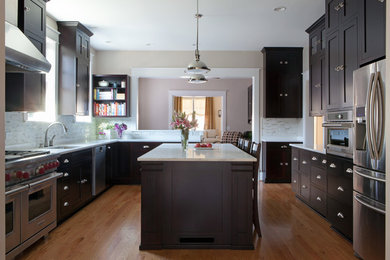 Mid-sized elegant l-shaped medium tone wood floor kitchen photo in Nashville with dark wood cabinets, marble countertops, stainless steel appliances, an island, an undermount sink, shaker cabinets, gray backsplash and stone tile backsplash
