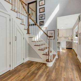 Klassischer Eingang mit Foyer, grauer Wandfarbe, braunem Holzboden, Einzeltür, Glastür, braunem Boden und Treppe in New York
