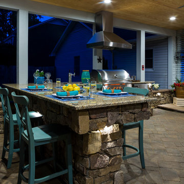 Covered outdoor area with fireplace, grill island and paver patio