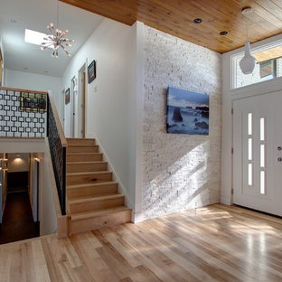 Foto på en stor retro foajé, med vita väggar, ljust trägolv, en dubbeldörr och en vit dörr