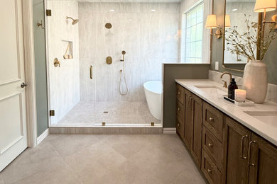 Large transitional master beige tile and porcelain tile ceramic tile, beige floor and double-sink bathroom photo with shaker cabinets, brown cabinets, an undermount sink, quartzite countertops, a hinged shower door, beige countertops and a built-in vanity