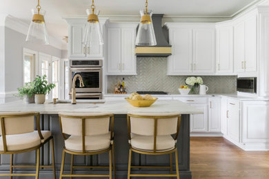 Mid-sized transitional single-wall medium tone wood floor and brown floor eat-in kitchen photo in Charlotte with an undermount sink, raised-panel cabinets, white cabinets, marble countertops, gray backsplash, ceramic backsplash, stainless steel appliances, an island and white countertops