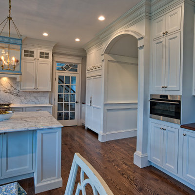 Eat-in kitchen - large traditional u-shaped medium tone wood floor and brown floor eat-in kitchen idea in Philadelphia with a farmhouse sink, beaded inset cabinets, white cabinets, quartz countertops, white backsplash, quartz backsplash, stainless steel appliances, an island and white countertops