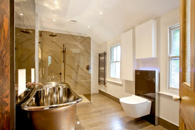 This is an example of a large contemporary family bathroom in Oxfordshire with a freestanding bath, a walk-in shower, a wall mounted toilet, multi-coloured tiles, beige walls, wood-effect flooring, multi-coloured floors and an open shower.