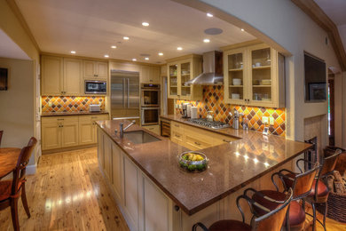 Mid-sized elegant u-shaped light wood floor open concept kitchen photo in San Francisco with an undermount sink, shaker cabinets, yellow cabinets, quartzite countertops, multicolored backsplash, ceramic backsplash, stainless steel appliances and a peninsula