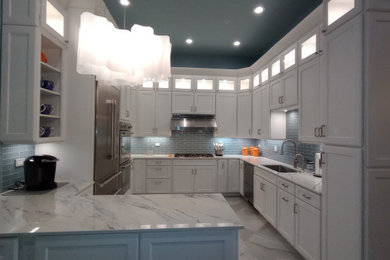 Large transitional u-shaped porcelain tile and multicolored floor enclosed kitchen photo in New York with an undermount sink, beaded inset cabinets, white cabinets, quartz countertops, blue backsplash, glass tile backsplash, stainless steel appliances, a peninsula and multicolored countertops