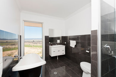 Modern master bathroom in Canberra - Queanbeyan with white cabinets, a freestanding tub, a one-piece toilet, black tile, ceramic tile, a drop-in sink, laminate benchtops, a hinged shower door and white benchtops.