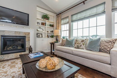 Mid-sized transitional open concept medium tone wood floor and brown floor family room photo in Other with gray walls, a standard fireplace, a tile fireplace and a wall-mounted tv