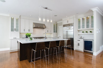 Inspiration for a large transitional l-shaped medium tone wood floor eat-in kitchen remodel in Other with an undermount sink, recessed-panel cabinets, white cabinets, quartz countertops, white backsplash, porcelain backsplash, stainless steel appliances and an island