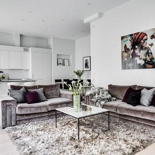 Inredning av ett modernt stort allrum med öppen planlösning, med ett finrum, vita väggar och ljust trägolv