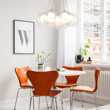 Glass bubble cluster chandelier over a dining table with orange chairs — Mirodem