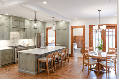 Inspiration for a craftsman medium tone wood floor and red floor eat-in kitchen remodel in Other with an undermount sink, beaded inset cabinets, green cabinets, quartzite countertops, white backsplash, porcelain backsplash, stainless steel appliances, an island and white countertops