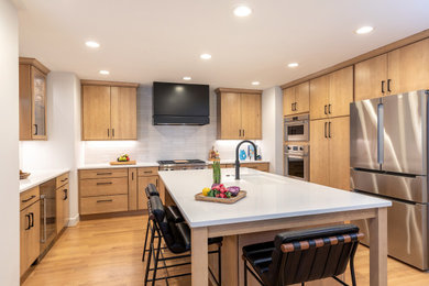 Open concept kitchen - mid-sized contemporary u-shaped light wood floor and brown floor open concept kitchen idea in Raleigh with an undermount sink, flat-panel cabinets, light wood cabinets, quartz countertops, white backsplash, porcelain backsplash, stainless steel appliances, an island and white countertops