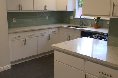 Kitchen - mid-sized transitional porcelain tile and black floor kitchen idea in Los Angeles with flat-panel cabinets, white cabinets, quartz countertops, green backsplash, glass tile backsplash and no island