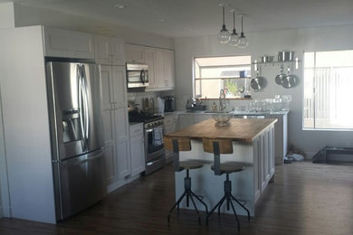 Eat-in kitchen - contemporary l-shaped medium tone wood floor eat-in kitchen idea in Los Angeles with an undermount sink, shaker cabinets, white cabinets, quartz countertops, white backsplash, subway tile backsplash, stainless steel appliances and an island