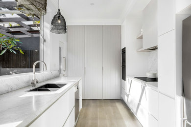Inspiration for a mid-sized contemporary single-wall kitchen pantry in Sydney with a drop-in sink, shaker cabinets, beige cabinets, marble benchtops, grey splashback, marble splashback, stainless steel appliances, light hardwood floors, with island, beige floor and grey benchtop.